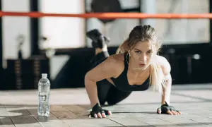 Femme faisant des pompes, un excellent exercice pour bras fripés. Elle est concentrée, dans une salle de sport.