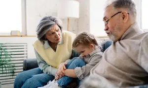 Un couple âgé discute avec inquiétude d'un enfant, peut-être un motif de refus droit de visite grand-parent.
