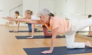 Trois femmes pratiquent un exercice jambe en équilibre sur un tapis de yoga.