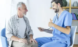 Un médecin rassure un patient âgé, lui expliquant l'espérance de vie après ablation de la prostate. Le docteur fait un pouce levé.