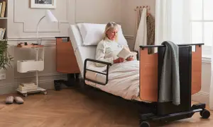 Une femme lit dans un lit médicalisé. Ce type de table de lit médicalisé est souvent éligible au remboursement de la Sécurité Sociale.