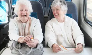 Deux femmes âgées rient à bord d'un train, profitant du transport gratuit pour personne âgée.