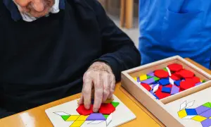 Un homme âgé assemble un puzzle coloré, un des nombreux jeux pour personnes âgées conçus pour stimuler l'esprit.