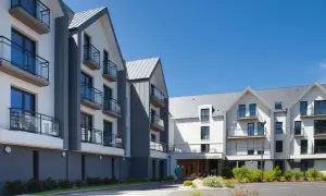 Bâtiments modernes avec balcons sous un ciel bleu. Découvrez les jardins d'Arcadie tarifs pour un séjour paisible.