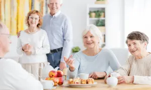 Des aînés souriants partagent un moment convivial autour d'un thé et de pâtisseries. Une définition de la marpa : un lieu de vie chaleureux pour seniors.