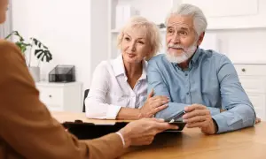 Un couple âgé discute avec un conseiller, inquiet d'un possible abus de procuration sur compte bancaire.
