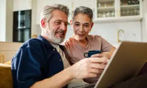 Couple souriant regardant un ordinateur portable, discutant du tarif ehpad pour un couple.