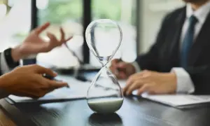 Sablier au premier plan, symbolisant le temps qui passe. Discussion sur combien de temps pour toucher l'argent d'une succession.