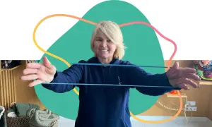 Une femme souriante fait des exercices avec un élastique, parfaite pour un programme de mise en forme 60 ans et plus.