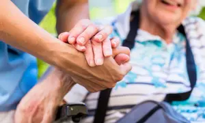 Une main plus jeune tient une main âgée. L'âge limite pour être tuteur est une question importante pour assurer le bien-être des personnes vulnérables.