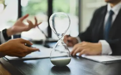 Sablier au premier plan, symbolisant le temps qui passe. Discussion sur combien de temps pour toucher l'argent d'une succession.