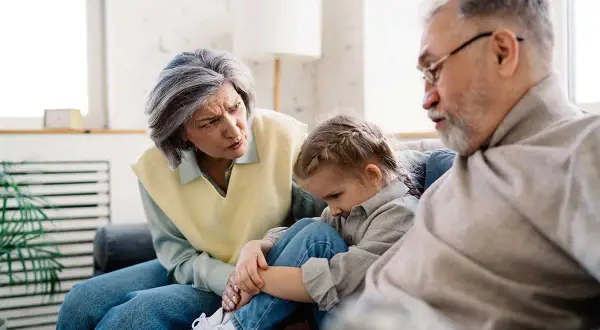Un couple âgé discute avec inquiétude d'un enfant, peut-être un motif de refus droit de visite grand-parent.