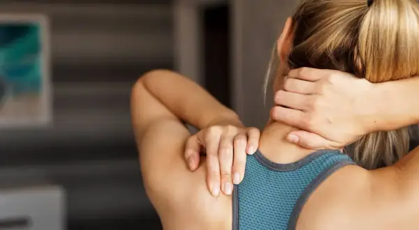 Femme se massant la nuque, cherchant soulagement pour son arthrose cervicale. Des exercices doux peuvent aider.