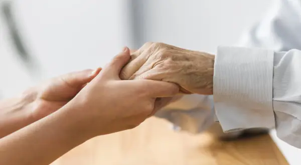 Deux mains se serrent, symbolisant la mise sous protection d'une personne âgée. Un geste de tendresse et de soutien.