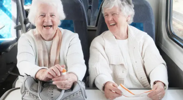 Deux femmes âgées rient à bord d'un train, profitant du transport gratuit pour personne âgée.