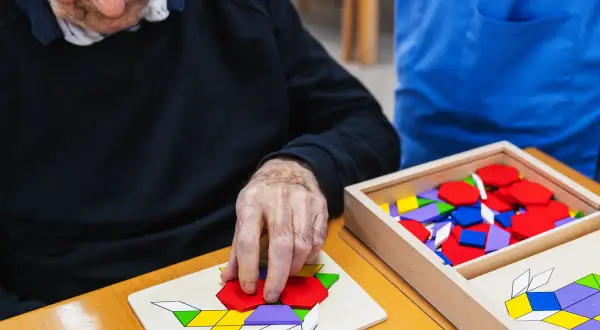 Un homme âgé assemble un puzzle coloré, un des nombreux jeux pour personnes âgées conçus pour stimuler l'esprit.