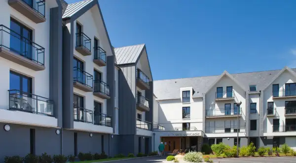Bâtiments modernes avec balcons sous un ciel bleu. Découvrez les jardins d'Arcadie tarifs pour un séjour paisible.