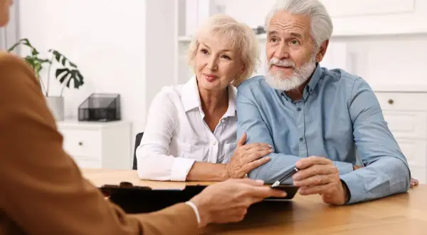 Un couple âgé discute avec un conseiller, inquiet d'un possible abus de procuration sur compte bancaire.