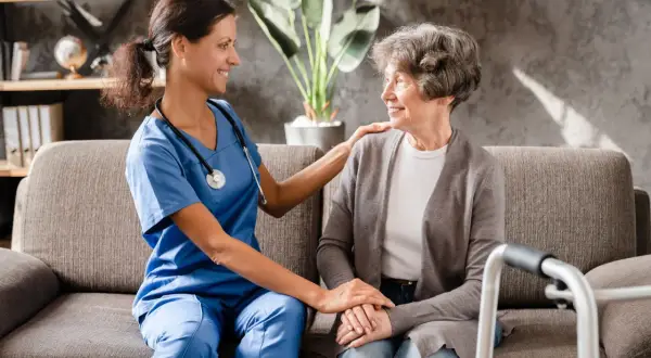 Aide-soignante réconfortant une patiente, évoquant les avantages fiscaux maladie parkinson.