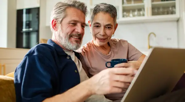 Couple souriant regardant un ordinateur portable, discutant du tarif ehpad pour un couple.