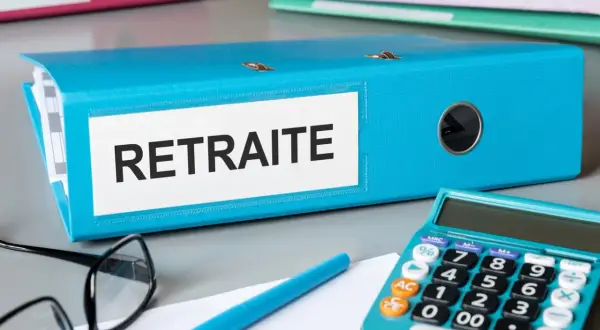 Dossier bleu "Retraite" sur un bureau, avec une calculatrice, des lunettes et un stylo. L'aspa montant est peut-être dans ce dossier.