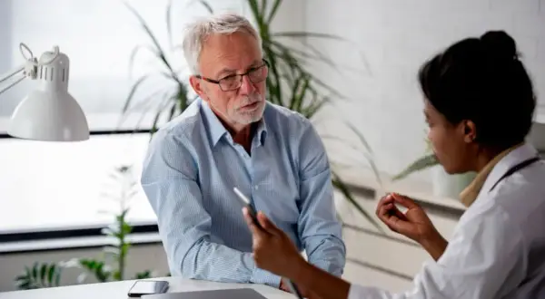 Un médecin discute avec un patient, lui expliquant les détails d'un certificat médical circonstancié.