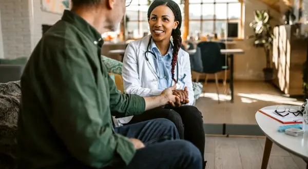 Une médecin rassure un patient, lui tenant la main. La question "peut-on sortir des soins palliatifs" est abordée avec espoir et soutien.