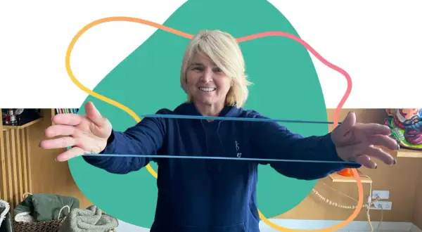 Une femme souriante fait des exercices avec un élastique, parfaite pour un programme de mise en forme 60 ans et plus.