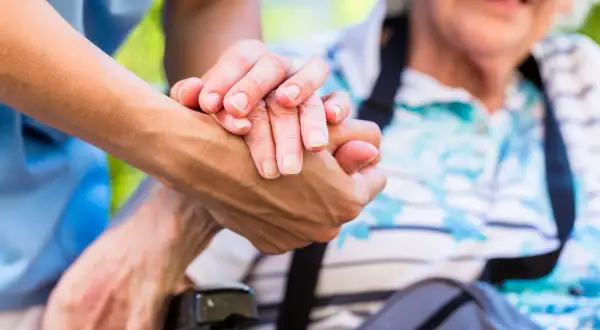 Une main plus jeune tient une main âgée. L'âge limite pour être tuteur est une question importante pour assurer le bien-être des personnes vulnérables.
