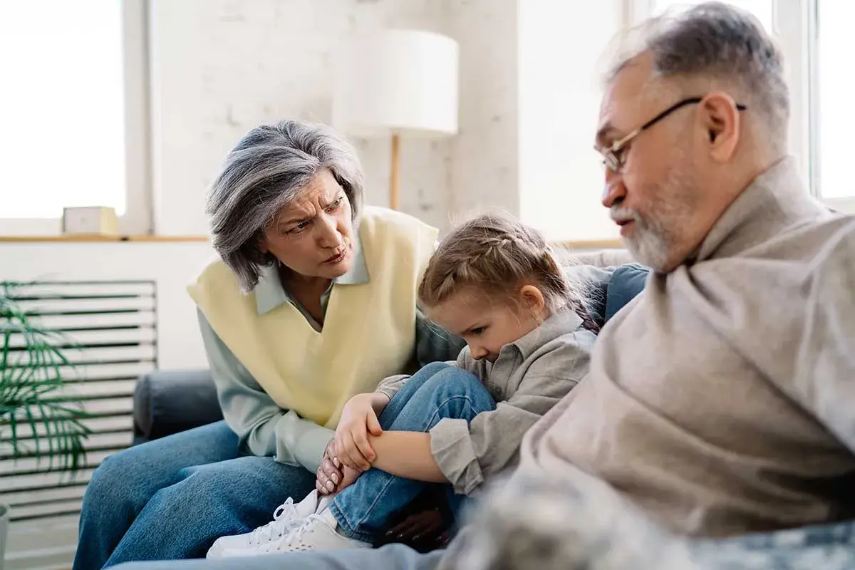 Un couple âgé discute avec inquiétude d'un enfant, peut-être un motif de refus droit de visite grand-parent.