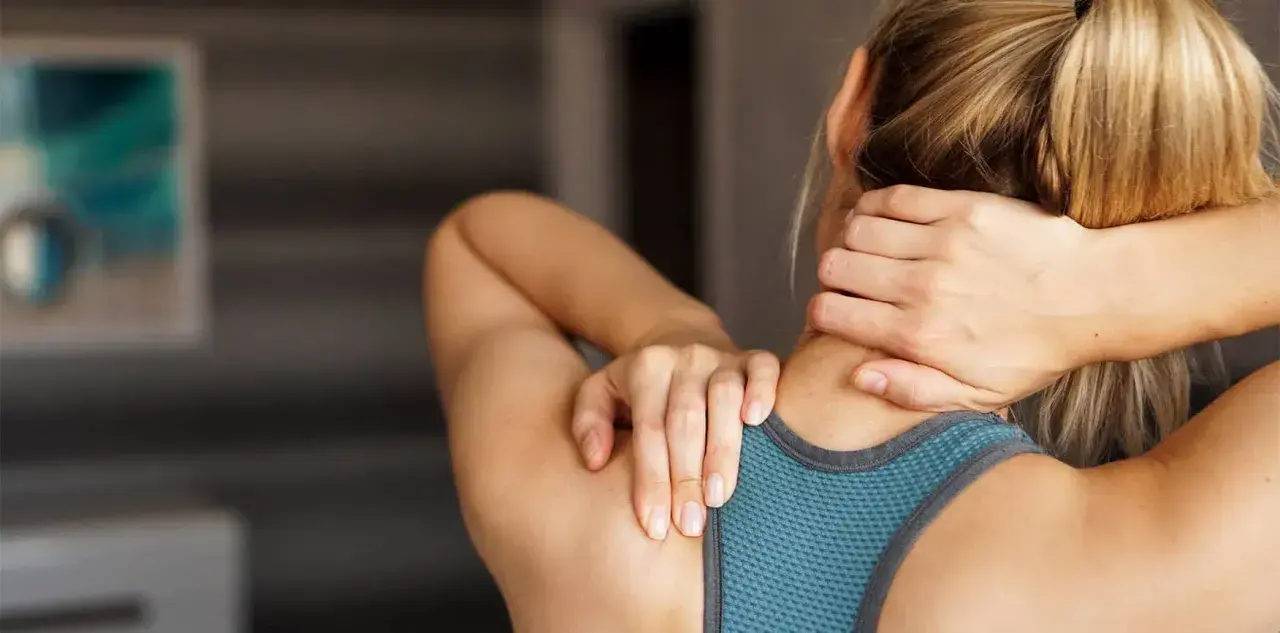 Femme se massant la nuque, cherchant soulagement pour son arthrose cervicale. Des exercices doux peuvent aider.