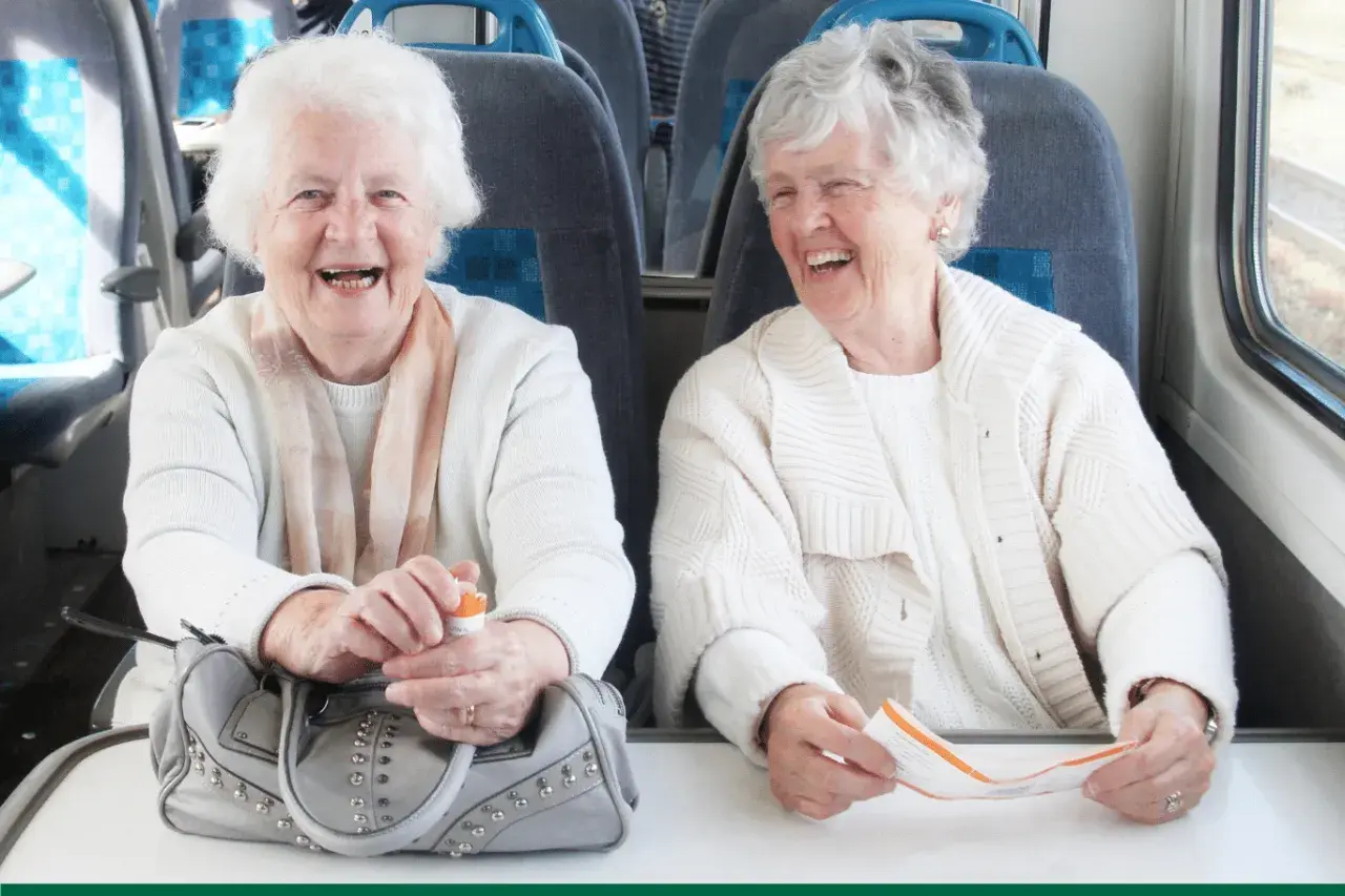 Deux femmes âgées rient à bord d'un train, profitant du transport gratuit pour personne âgée.