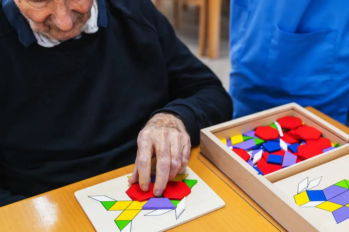 Un homme âgé assemble un puzzle coloré, un des nombreux jeux pour personnes âgées conçus pour stimuler l'esprit.