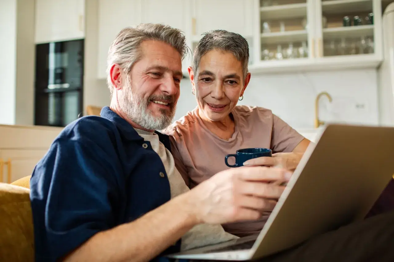 Couple souriant regardant un ordinateur portable, discutant du tarif ehpad pour un couple.