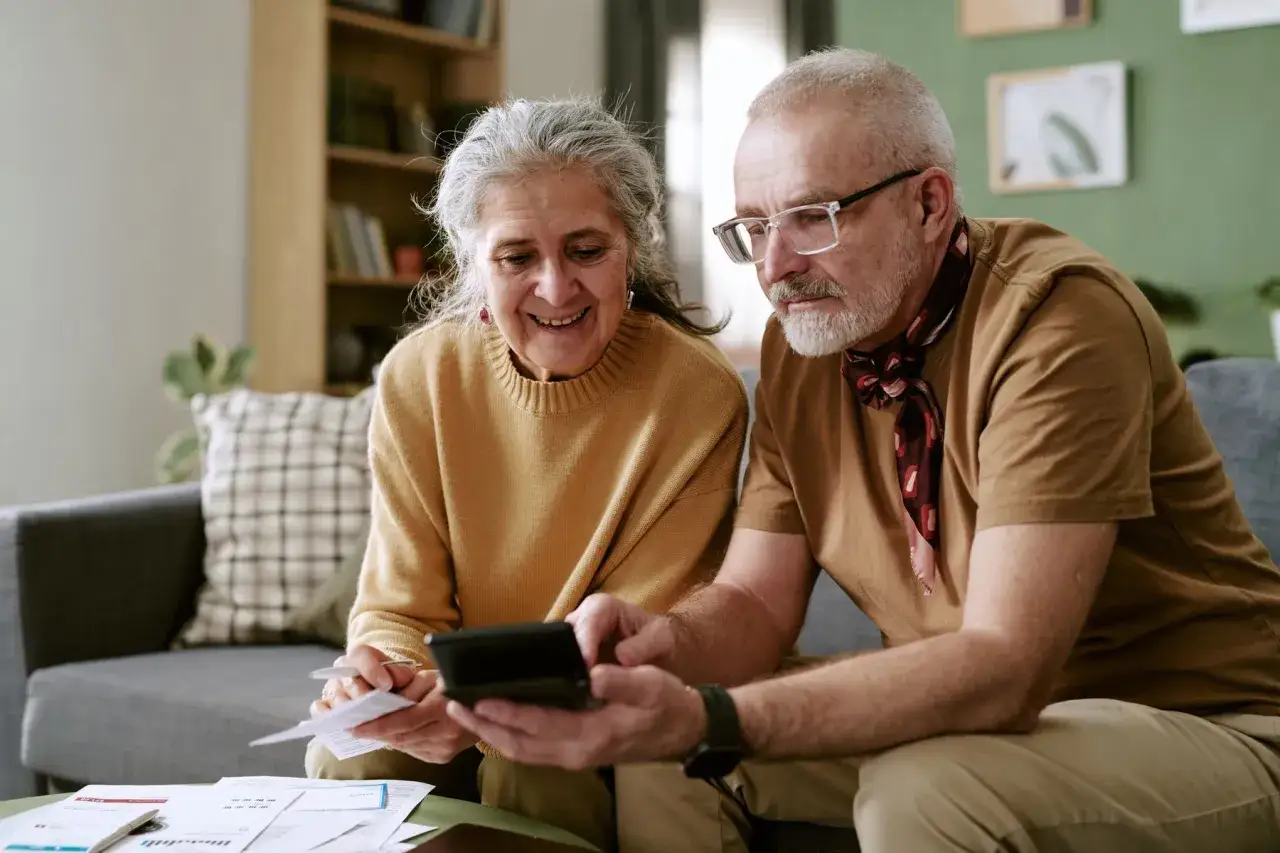 Couple &acirc;g&eacute; calculant leur budget pour un logement senior pas cher. Ils semblent satisfaits de leurs &eacute;conomies.