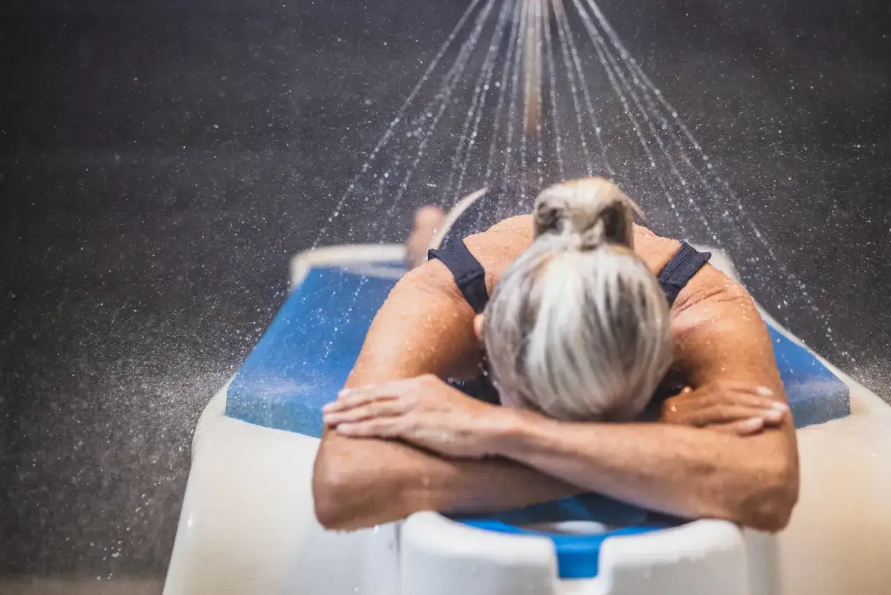 Femme d&eacute;tendant sous une douche &agrave; jet, profitant des bienfaits de la thalasso. Renseignez-vous sur le remboursement mutuelle pour vos soins.