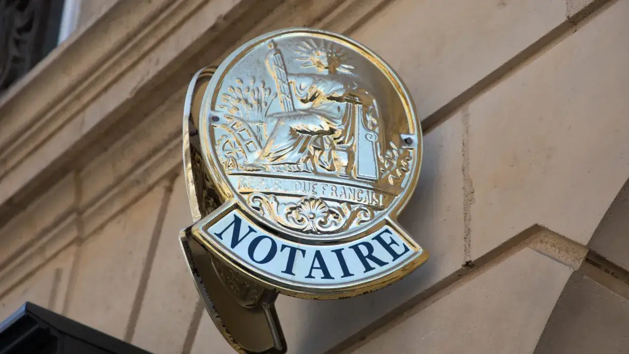 Plaque de notaire dorée. Le délai pour toucher l'argent d'une succession peut varier.