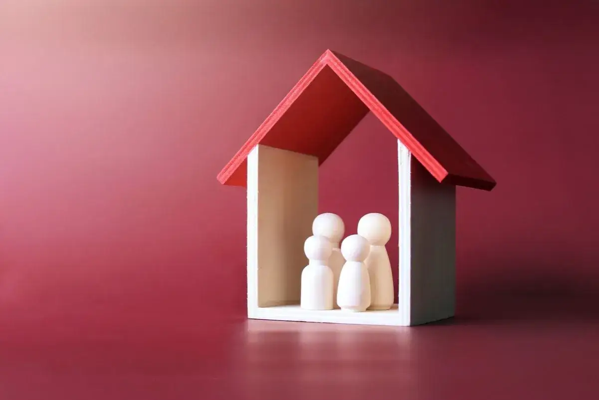 Petites figurines en bois représentant une famille sous un toit rouge. Le usufruitier quitte la maison, laissant derrière lui les souvenirs.