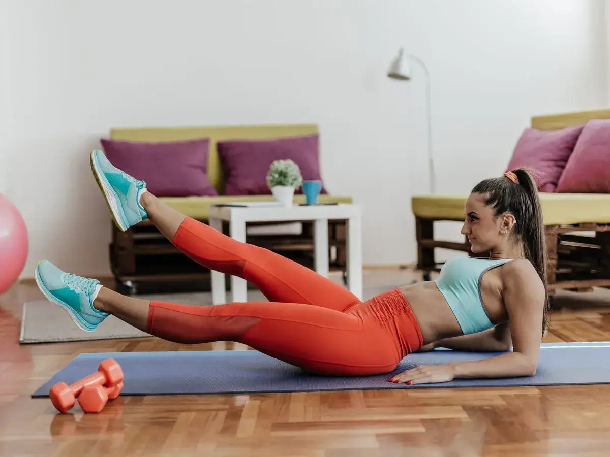 Femme effectuant un exercice pour le bas du ventre, allongée sur un tapis, jambes levées.