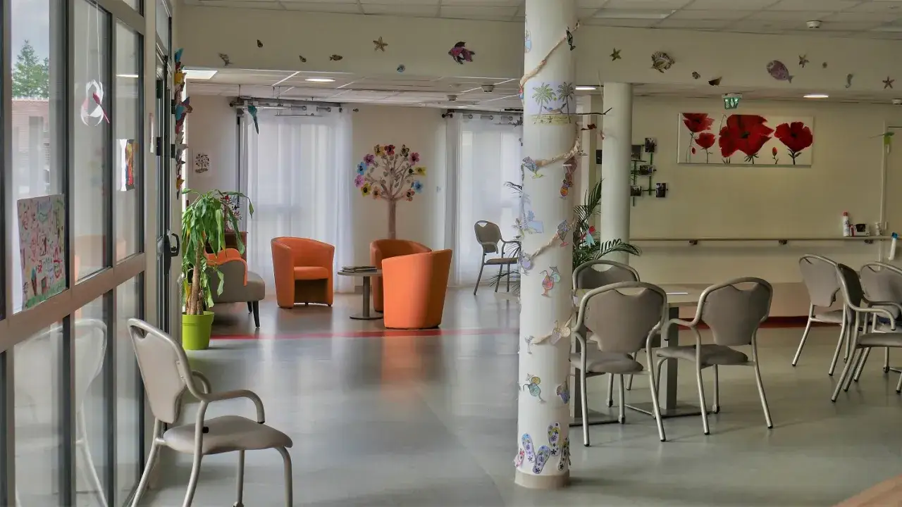 Salon lumineux d'un ehpad Alzheimer, décoré de dessins d'enfants et de couleurs vives pour égayer le quotidien des résidents.