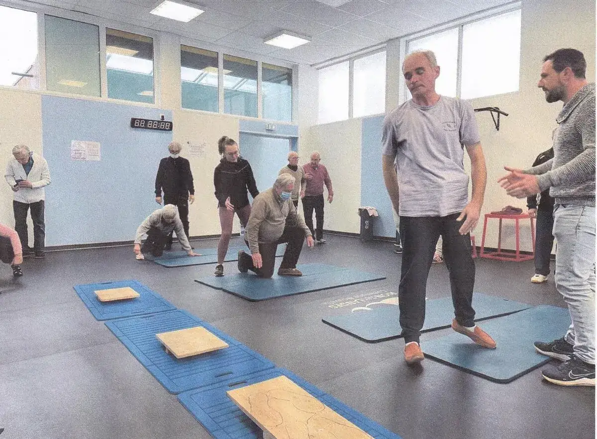 Des personnes âgées font des exercices, peut-être pour les avantages fiscaux maladie Parkinson. Un coach les supervise.