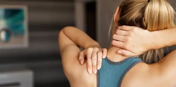 Femme se massant la nuque, cherchant soulagement pour son arthrose cervicale. Des exercices doux peuvent aider.