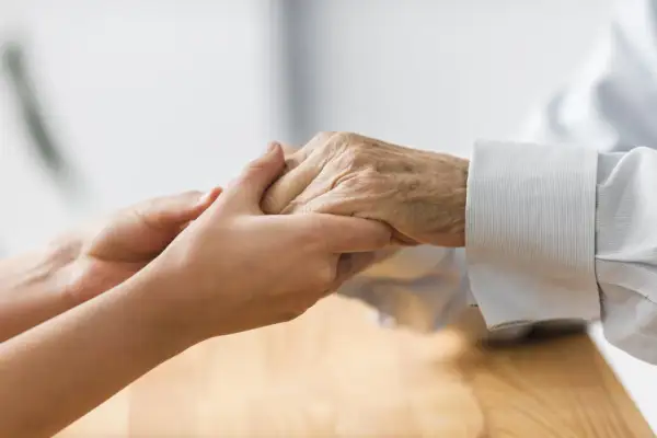 Deux mains se serrent, symbolisant la mise sous protection d'une personne âgée. Un geste de tendresse et de soutien.