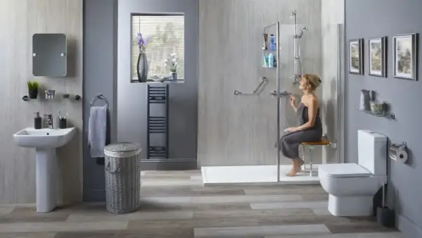 Salle de bain adaptée pour seniors. Une femme utilise une douche avec siège, bénéficiant de l'aide gouvernementale pour une meilleure autonomie.