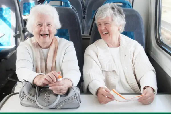 Deux femmes âgées rient à bord d'un train, profitant du transport gratuit pour personne âgée.