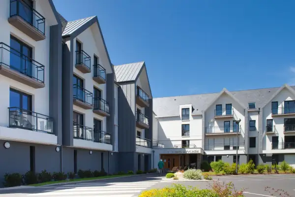 Bâtiments modernes avec balcons sous un ciel bleu. Découvrez les jardins d'Arcadie tarifs pour un séjour paisible.