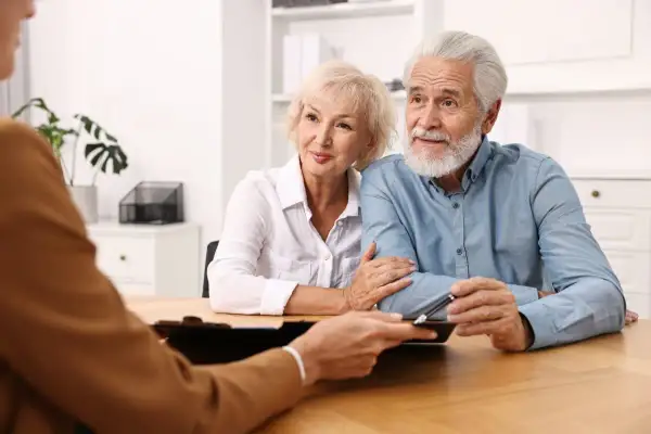 Un couple âgé discute avec un conseiller, inquiet d'un possible abus de procuration sur compte bancaire.