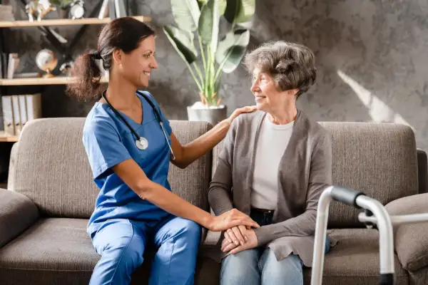 Aide-soignante réconfortant une patiente, évoquant les avantages fiscaux maladie parkinson.