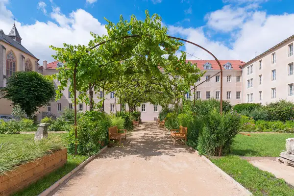 Allée ombragée des jardins d'Arcadie, invitant à la contemplation. Conditions d'admission : trouver la sérénité. Bancs de bois sous la vigne.