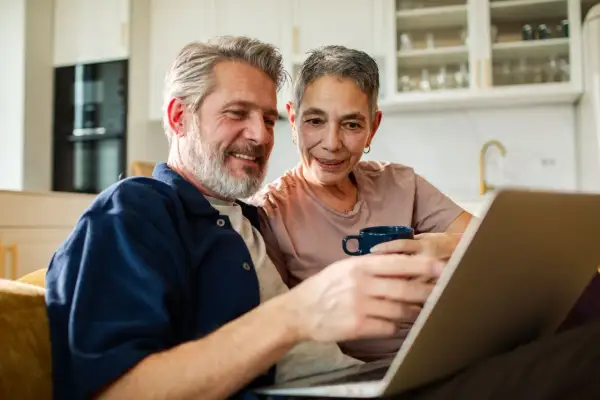 Couple souriant regardant un ordinateur portable, discutant du tarif ehpad pour un couple.